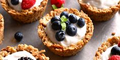 some fruit and yogurt cups are sitting on a tray with strawberries, raspberries, blueberries, and more