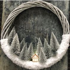 a wreath decorated with snow and pine trees in the shape of a house surrounded by branches