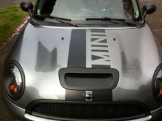 the front end of a small car with an emblem on it's hood, parked in a parking lot