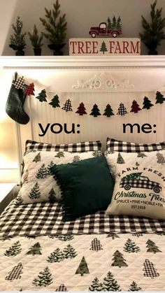 a bed topped with pillows and blankets covered in christmas tree decorations next to a sign that says you me