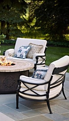 an outdoor fire pit surrounded by chairs and tables