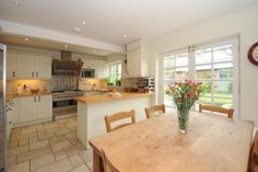 a kitchen with a table and chairs next to a window that has flowers in it