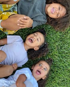 three children laying in the grass with their mouths open