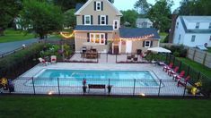 a backyard with a swimming pool and patio furniture in the evening time, surrounded by lawn chairs