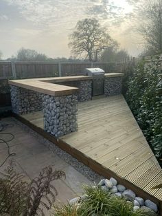 a wooden bench sitting on top of a dry grass field next to a lush green forest