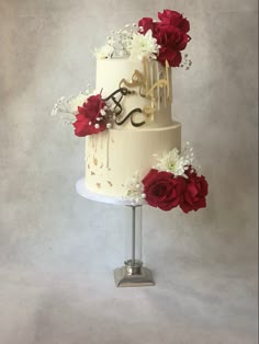 a three tiered cake with flowers and scissors on the top is decorated with red roses