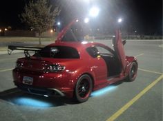 a red car parked in a parking lot at night