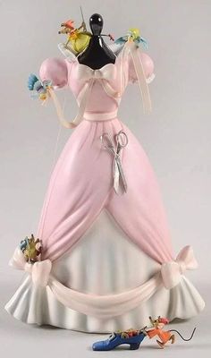 a figurine that is on top of a dress and some toy figures next to it