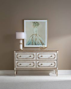 a white dresser sitting next to a painting on top of a wall