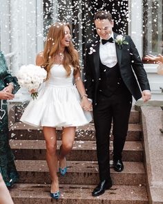 a bride and groom walk down the steps as confetti falls around them