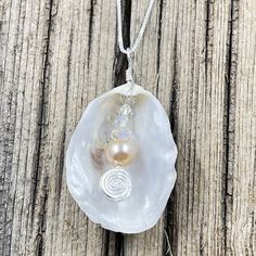 This beautiful pendant is made from a natural white oyster found on the beaches in the Cape May area. A spectacular metallic fresh water pearl is nestled inside the oyster shell showing off the treasure inside. The shell was then wire wrapped with sterling silver wire. The pendant measures 2 inches in length from the top of the bail and 1 inches wide. The pendant is on a 16" sterling silver box chain but other lengths are available in the below options. Silver Shell With Pearl Pendant, Silver Shell Necklace With Pearl Pendant As Gift, Silver Shell Gift, Silver Shell Jewelry With Pearl Charm, Silver Shell Necklace With Pearl Pendant, Silver Shell Necklaces With Pearl Charm, Silver Mother Of Pearl Shell Necklace With Pearl Pendant, Silver Pearl Shell Necklace Gift, Silver Pearl Shell Necklace As A Gift