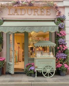 a store front with flowers on the side and a cart in front that says laduree