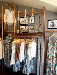 a rack with clothes hanging on it in a clothing store next to pictures and framed photos