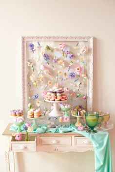 a dessert table with cupcakes and pastries on it in front of a painting