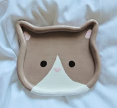 a brown and white cat shaped dish on a bed