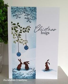 a christmas card with two rabbits hanging from a tree