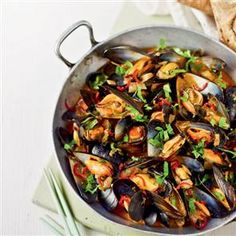 a pan filled with mussels and garnished with cilantro sauce