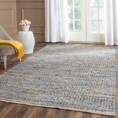 a large rug in the middle of a living room with wooden floors and white curtains