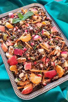 a platter filled with fruit and nuts on top of a blue cloth covered table