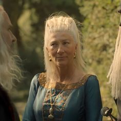 an older woman with white hair standing next to two other people