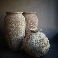 two large vases sitting next to each other on a black surface with dark background