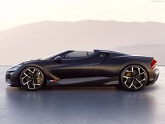 a black sports car parked on top of a wet ground with mountains in the background