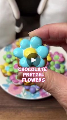 a person is holding a chocolate pretzel in front of a plate with flowers on it