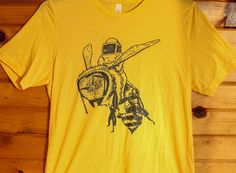 a yellow t - shirt with a drawing of a bee holding a honeybee on it