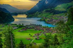 an aerial view of a small village in the middle of a lake surrounded by mountains