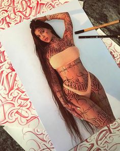 a woman with tattoos on her body laying in front of a piece of art paper