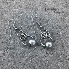 two silver balls are hanging from hooks on the concrete floor, one has been made to look like an earring