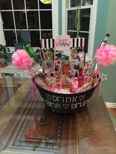 a basket filled with lots of bottles and pink pom poms on top of a table