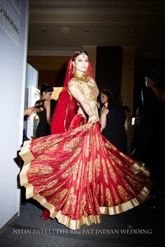 a woman in a red and gold bridal gown is posing for the camera while others look on