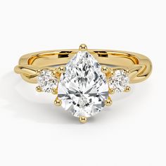 a yellow gold engagement ring with three pear shaped diamonds on the band and an oval cut diamond