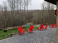 several red chairs sitting on top of a gravel covered field