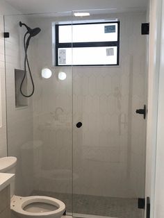 a white toilet sitting next to a shower stall in a bathroom under a window with a skylight