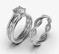 two white gold wedding rings with an intricate design on each side and a round diamond in the center