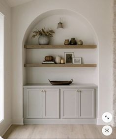 a white room with shelves and vases on top of them, along with pictures