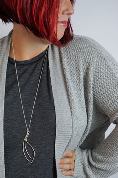 Soft curves form an elegant, handcrafted pendant on a long chain for the perfect pop for your every day style. Available in tarnish-resistant Argentium silver with a silver chain, matte black steel with an oxidized silver chain, or bronze with a bronze chain. Approximately 3 1/2" tall and 1 1/8" wide. Comes on a 30" long chain with clasp. Each necklace is handmade to order and may vary slightly from those shown. Please allow 2-3 days for your necklace to ship. Comes in a gift box tied with a rib Minimalist Gunmetal Metal Necklace, Silver Long Drop Necklaces For Everyday, Everyday Silver Long Drop Necklace, Everyday Oxidized Metal Necklace, Everyday Long Drop Silver Necklace, Elegant Stainless Steel Necklace With Oxidized Finish, Modern Gunmetal Necklace With Oxidized Finish, Argentium Silver, Oxidized Silver