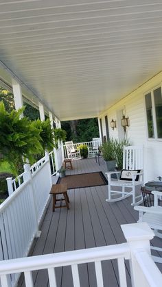 a white porch with rocking chairs and tables on the front deck, along with potted plants