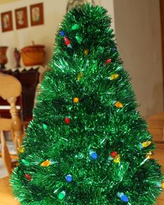 a green christmas tree sitting on top of a wooden table