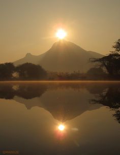 the sun is setting over a mountain and lake