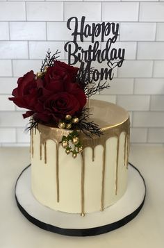 a white cake with gold drips and red roses on top that says happy birthday mom