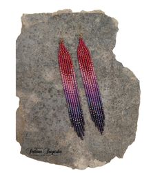 two pairs of beaded earrings sitting on top of a rock