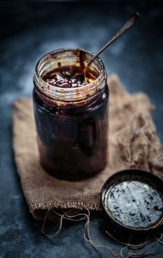 a glass jar filled with liquid sitting on top of a cloth next to a spoon