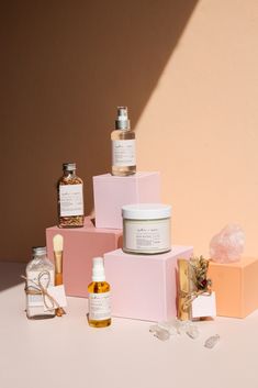 several different types of skin care products sitting on top of each other in front of a pink wall