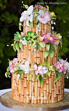 a three tiered cake decorated with flowers and bamboo