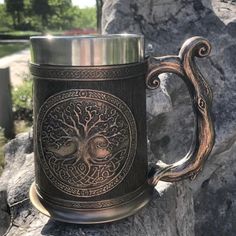 a metal mug sitting on top of a rock