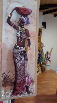 a woman in an african dress is holding up a painting