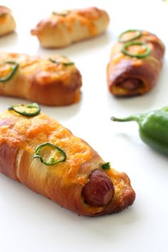 hot dogs wrapped in bread with peppers and jalapenos on the side, ready to be eaten